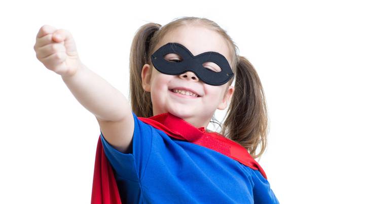 Kleines Mädchen mit rotem Umhang und Maske spielt Superheld